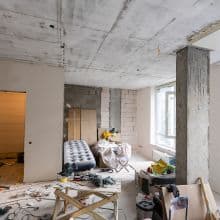 Renovierungsarbeiten in einer Neubauwohnung mit sichtbaren Rohren und Baumaterialien, in einem modernen Innenraum.