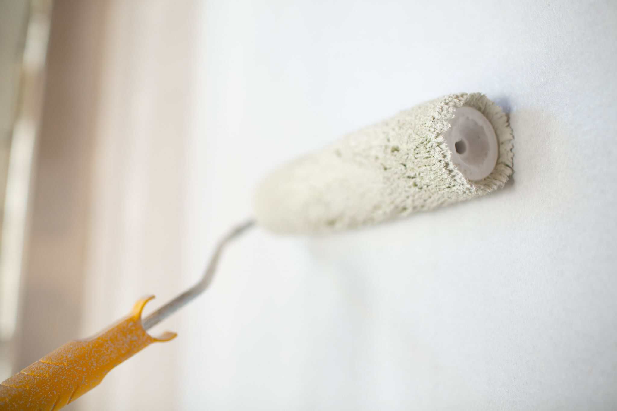 Sanierungsarbeiten an der Wand mit Pinsel und Farbrolle, professionelles Malerhandwerk, Innenraumgestaltung, Tapezieren und Renovierung durch artur-bausanierung.de.